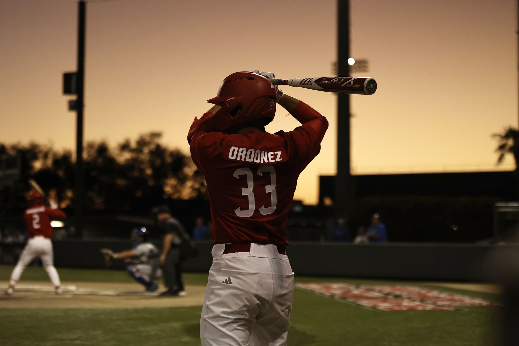 Erick, number 33, on deck at sunset in a red college uniform